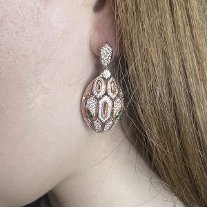 gold plated snake earrings with emerald detail worn on model