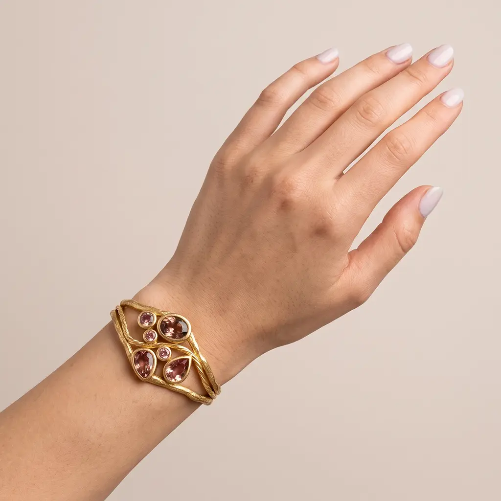 14K yellow gold bracelet on a raised wrist, the lab-grown zultanite turned rose pink in warm lamp light