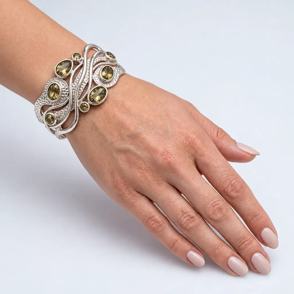 Silver cuff bracelet with olive green lab-grown zultanite worn on a woman's wrist in daylight